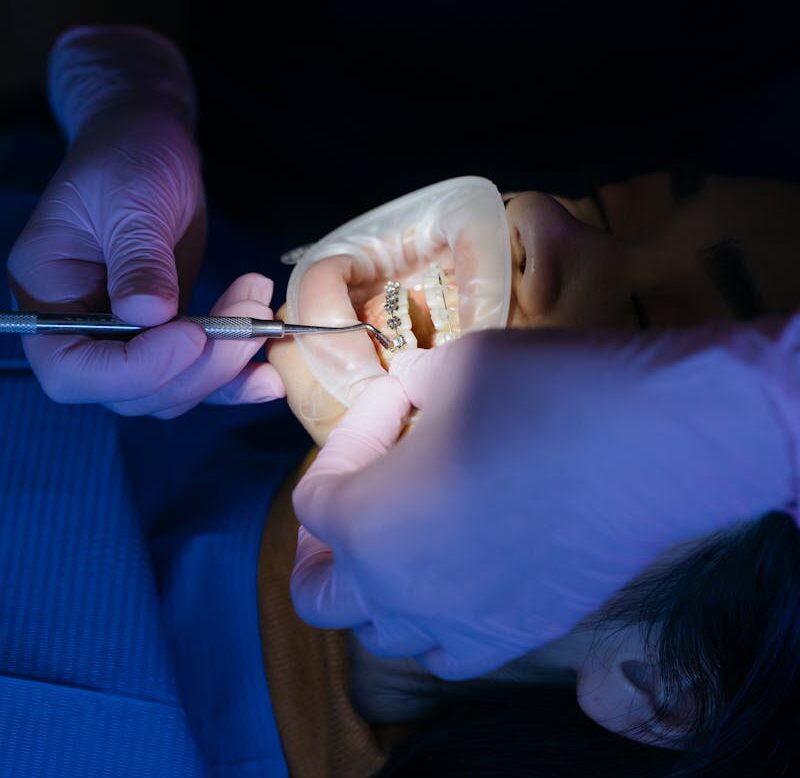 Dentist examining a patient's teeth using tools in a clinical setting.